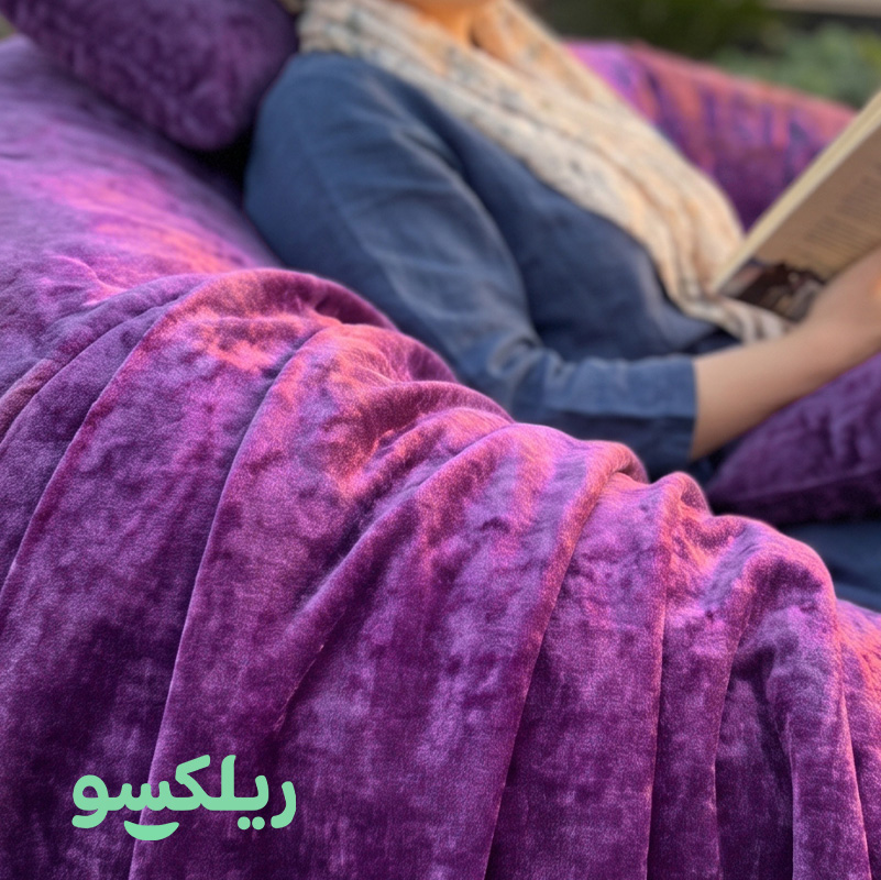 نمای نزدیک پارچه مخمل مبل شنی لاکچری ریلکسو — بافت مخمل بنفش با نور طبیعی